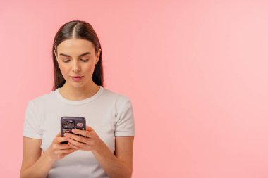 Bir telefona odaklanmış, canlı pembe arka planlı minimalist bir şekilde resmedilmiş..