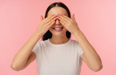 Parlak kompozisyon, kendine güvenen, gülümseyen genç bir birey gözlerini kapatırken canlı pembe bir arka plana karşı elleri kullanıyor..