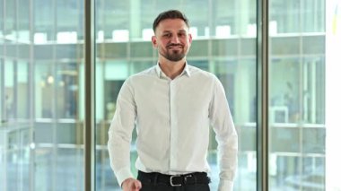 Kendine güvenen iş adamı modern ofiste onaylar. Gülümsüyor ve olumlu, başarılı tavırlar sergiliyor..