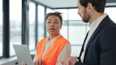 Profesyonel mimar ve inşaat mühendisi modern ofis alanındaki bir projeyi tartışıyor. Mühendislerden oluşan çok uluslu bir ekip, Afrikalı Amerikalı bir kadın ve bir emlak yatırımında çalışan beyaz bir erkek..