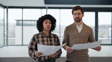 Profesyonel meslektaşlar geniş bir ofiste planları tartışırlar. Yeni çalışma alanlarını planlarken ilham verici ve hırslı hissediyorlar..