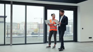 Profesyonel mimar ve yatırımcı modern ofis alanının planlarını tartışıyor. İş toplantısında odaklanmış ve kararlı hissediyorlar..