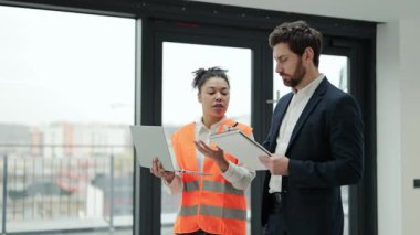 Ticari gayrimenkul yatırımlarında uluslararası işbirliği anlaşması. Profesyonel mimar ve inşaat mühendisi yeni bir ofis alanında inşaat planlarını tartışıyor. Odaklanmış ve kararlı hissediyorlar..