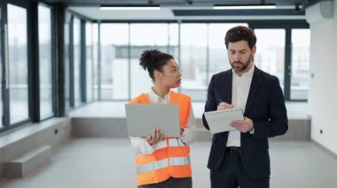 Kadın profesyonel mühendis ve yatırımcı boş modern ofiste inşaat planlarını tartışıyor. Ciddi ve konsantrasyonla çalışıyorlar. Ticari gayrimenkul yatırımlarında uluslararası işbirliği anlaşması.