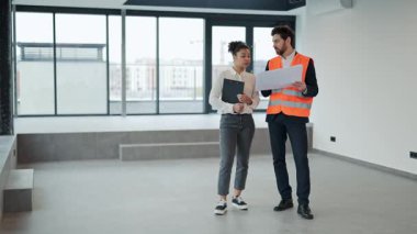 Profesyonel yatırımcı ve mimar modern boş ofis alanının planlarını tartışıyor. İş ortakları plan yapar, strateji kurar, ilham verici ve kendinden emin hisseder..