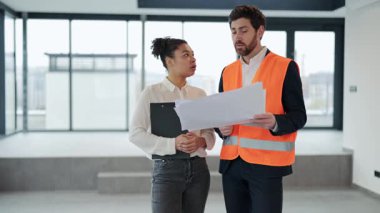 Profesyonel mimar ve yatırımcı yeni ofis alanının planlarını tartışıyor. Resmi olarak giyinmişler, işbirliği yapıyorlar, odaklanıyorlar ve tatmin oluyorlar..