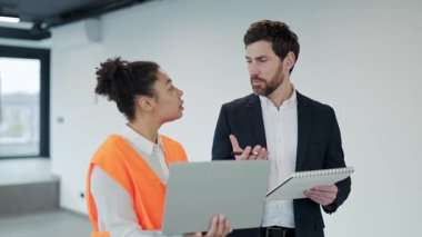 Profesyonel mimar ve inşaat mühendisi bir projeyi tartışıyor. Modern ofis alanında kendilerini yaratıcı ve işbirlikçi hissediyorlar..