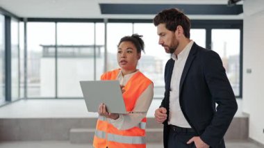 Afrika kökenli Amerikalı mimar ve inşaat mühendisi proje detaylarını modern ofiste tartışırlar. Takım çalışması ve iş birliği. Ticari gayrimenkul yatırımları.