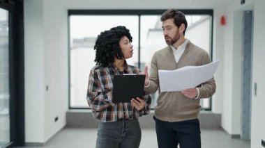 Profesyonel meslektaşlar yeni ofis alanının planlarını tartışıyor. Sıradan giysiler içinde bir kadın elinde bir not panosuyla iş adamına fikirlerini zekice açıklıyordu. Takım çalışması..