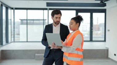 Profesyonel işadamı ve mimar yeni ofis alanında dizüstü bilgisayar kullanarak bir projeyi tartışıyor. Odaklanmış hissediyorlar. Ticari gayrimenkul yatırımları