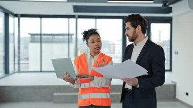 Kadın profesyonel mimar ve yatırımcı modern ofisin planlarını tartışıyor. Yatırımcı belgeleri elinde tutuyor ve mimar dizüstü bilgisayar kullanıyor. Başarılı takım çalışması, güven ve uzmanlık.