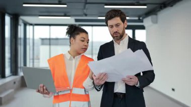 Afrika kökenli Amerikalı kadın profesyonel mimar ve erkek yatırımcı modern bir ofis binasının planlarını tartışıyor. Bir iş toplantısında odaklanmış, dikkatli ve ciddi hissediyorlar..