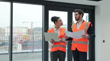 Profesyonel mimar ve mühendis inşaat halindeki bir binanın planlarını tartışıyor. Takım çalışması ve mimarlık uzmanlığı.