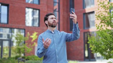 Hüsrana uğramış bir adam Wi-Fi sinyali alamaz ve cep telefonu çekmez. Hüsrana uğramış, mavi gömlekli girişimci dışarıda dikiliyor. Modern mimari, teknoloji ve iletişim.