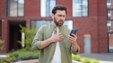 Hasta adamın portresi telefonunda kötü haber okurken göğsünde ağrı hisseder. Dışarıda dikiliyor ve günlük giysiler giyiyor..