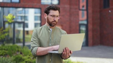 Ofis binasının dışında günlük giysiler içinde başarılı bir iş adamı. Laptop kullanan yakışıklı bir serbest yazar. Neşe, başarı, mutluluk, güven, iyi ruh hali.