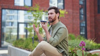 Gündelik giysiler içinde akıllı telefon kullanarak dışarıdaki sesli mesaj göndermekle meşgul. Kentsel yaşam tarzı, teknoloji, iş, iletişim.