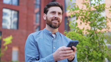 Ofisin yanındaki sokakta telefon kulübelerini kullanan yakışıklı bir adam. Sıradan bir gömlek giyiyor ve sakalı var. Mutlu iş adamı memnun oldu..