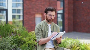Ofisin yanındaki defterde yakışıklı bir iş adamı yazıyor. Gözlüklü profesyonel adam dışarıda tuğla binanın yanında notlar alıyor. Başarılı erkek mutlu hissediyor..
