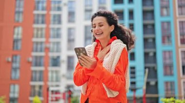 Şık giyinen heyecanlı kadın şehirde telefon, mutluluk ve eğlence kullanırken duygusal tepki veriyor..