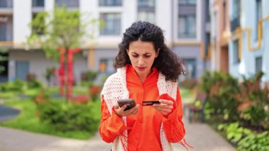 Akıllı telefon ve kredi kartıyla online ödeme yapmakta zorlanan kafası karışmış bir kadın. Kafası karışmış ve hayal kırıklığına uğramış hissediyor..