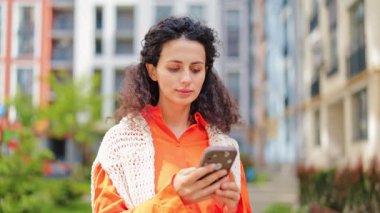 Şık bir kadın akıllı telefonunu tutarken diş ağrısını hisseder, apartmanın yakınında üzgün durur. Turuncu gömlek ve örgü yelek giymiş hayal kırıklığına uğramış bir kadın kendini iyi hissetmiyor..