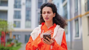 Parlak elbiseli endişeli bir kadın kötü haberler okuyor, stres yaşıyor, dışarıda endişe duyuyor. İnsan hayal kırıklığı, şok, keder, üzüntü hisseder..