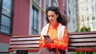 Açık havada telefon kullanan neşeli bir kadın. Şehirde akıllı telefon kullanan şık bir serbest meslek sahibi. Kürsüye mesaj yazan modern iş kadını.