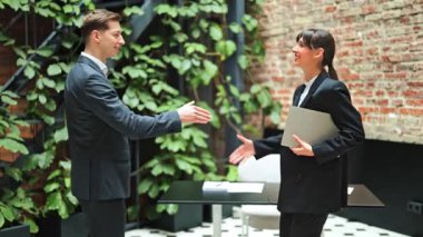 Başarılı bir iş kadını ve iş adamı el sıkışıyor ve konuşuyor. Modern ofiste resmi giysi toplantısında iş ortakları.