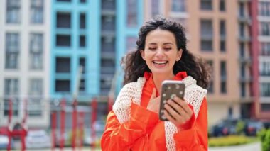 Şehirde telefon kullanan şık bir kadın. Güzel haberlerle mutlu olan heyecanlı kadın dışarıda piyango kazanıyor. Şehirde akıllı telefon kullanan şanslı kız..