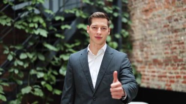 Takım elbiseli neşeli iş adamı onaylıyor. Modern ofiste başarılı bir adamın portresi. Olumlu duygular, mutlu olmak..