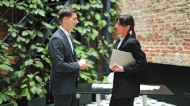 Resmi kıyafetler giyen işadamı ve iş kadını modern bir ofiste tartışıyorlar. Pozitif duygular, şık bir çalışma alanında meslektaşlar arasında etkili iletişim.