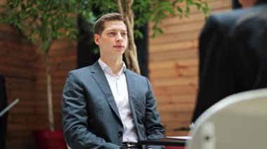 Takım elbiseli güvenilir işadamı iş toplantısına katılıyor. Profesyonel erkek modern ofiste dikkatle dinler. Resmi giyimde sakin ve odaklanmış bir uzman..