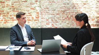 Başarılı bir işadamı ve iş kadını resmi bir ofis toplantısında sözleşme detaylarını tartışıyor. Odaklanmış, özenli ve profesyonel hissediyorlar..