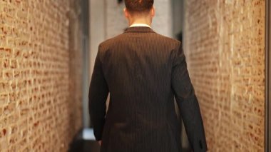 Takım elbiseli kendine güvenen bir işadamı deri çanta taşıyarak ofis koridorunda yürür. Kararlı ve odaklanmış hissediyor..