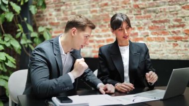 Resmi giyimde odaklanmış meslektaşlar dizüstü bilgisayarla çizelgeleri tartışırlar. İş ortakları modern ofisteki mali raporu analiz eder, güven ve konsantrasyonu ifade ederler.