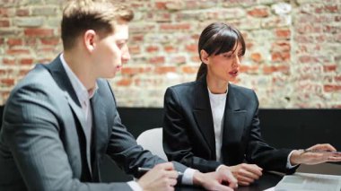 Resmi giyimde odaklanmış meslektaşlarım çatı katındaki bir masada bir projeyi tartışıyorlar. Konsantre ve ilgili hissediyorlar..