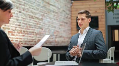 Kendine güvenen işadamı ve iş kadını modern ofiste pazarlık yapıyorlar. Profesyonel meslektaşlar sözleşme detaylarını tartışıyor, odaklanmış ve kararlı hissediyorlar.