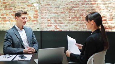 Kendine güvenen işadamı ve iş kadını modern bir ofiste tartışıyorlar. Sözleşme detaylarını tartışıyor ve profesyonel olarak iletişim kuruyorlar..