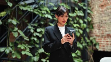 Takım elbiseli heyecanlı iş kadını dışarıda başarıyı kutluyor. Neşeli bayan girişimci telefondaki iyi haberden memnun..