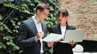 Ofiste bir projeyi tartışan kendine güvenen iş ortakları. İş kadını laptopta bilgi gösteriyor. Resmi giyimde birlikte çalışan ciddi iş ortakları..