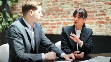 Profesyonel iş kadını ve resmi giyimli işadamı ofiste düzenlenen bir iş toplantısında yeni bir projeyi tartışıyorlar. Hevesli, kendinden emin ve motive hissediyorlar..