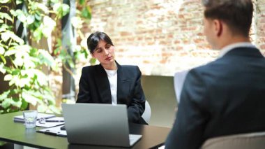 Ciddi bir iş kadını ve işadamı, modern bir ofiste yapılan bir iş toplantısında sözleşme detaylarını tartışırlar. Odaklanmış ve profesyonel hissediyorlar..