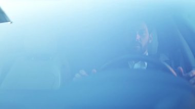 Şık takım elbiseli, kendine güvenen profesyonel işadamı lüks arabasını sürüyor, keyifli ve parlak bir günde önündeki yola odaklanmış görünüyor. İnsan mutlu ve mutlu.