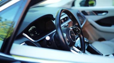 Koyu renk takım elbiseli profesyonel işadamı modern, gösterişli bir arabanın direksiyonunu sıkıca kavrıyor..