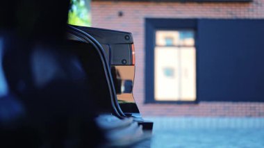 Açık hava konut ortamındaki lüks siyah araba bagajının pürüzsüz kapanması. Gelişmiş özellikler, araç sahiplerine kolaylık sağlayarak modern otomotiv teknolojisini ön plana çıkarıyor.