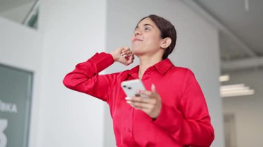 Başarılı Hintli iş kadını modern bir ofiste zaferi kutluyor. Parlak kırmızı bir gömlek giymiş, bu heyecanlı profesyonel deneyim onun akıllı telefonuna bakarken neşe ve başarı..