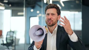 Sivri takım elbiseli ve beyaz gömlekli neşeli profesyonel erkek elinde megafonla çağdaş ofis ortamında önemli haberleri paylaşıyor..
