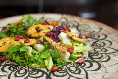 Bir tabak salata ve desenli bir tabak. Salata marul, salatalık ve havuçtan oluşur.