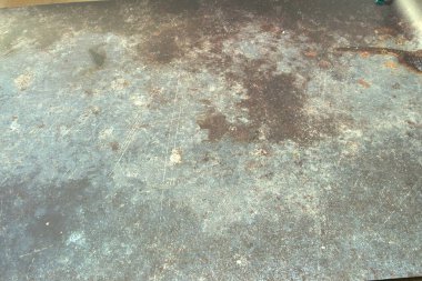 Kirli, gri zeminde birkaç leke var. Zemin kir ve kir içinde, soluk bir görünüm veriyor.